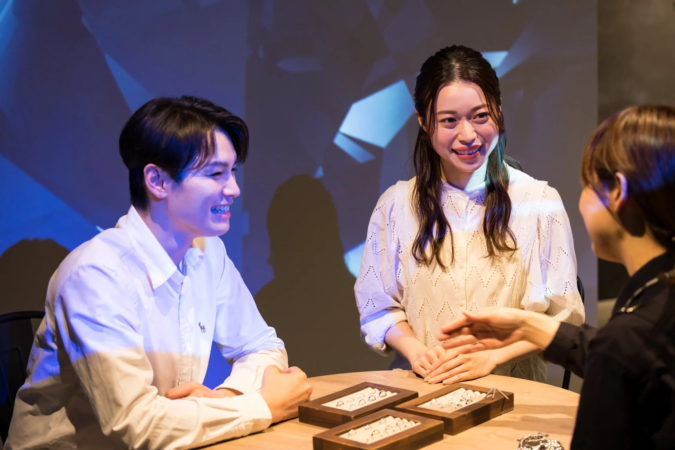 指輪を選んでいるカップルと店員の様子