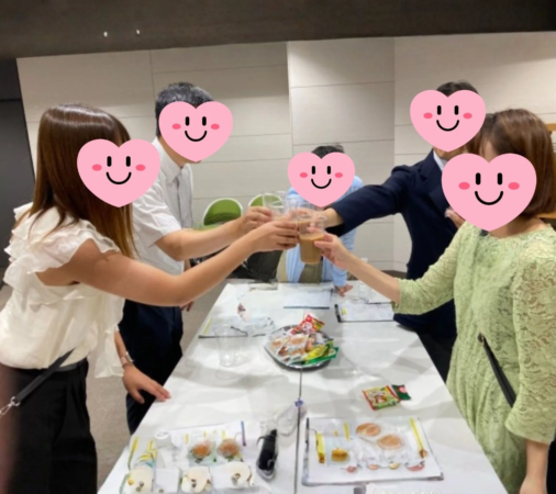 複数の人々がテーブルを囲み、飲み物を手に乾杯をしている様子です。和やかな雰囲気の中で交流を楽しむ懇親会やイベントの一場面を捉えています。