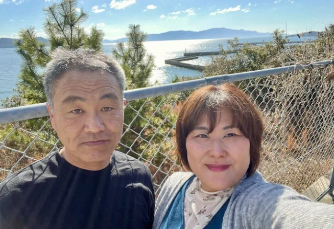 海を背景に自撮りするカップル