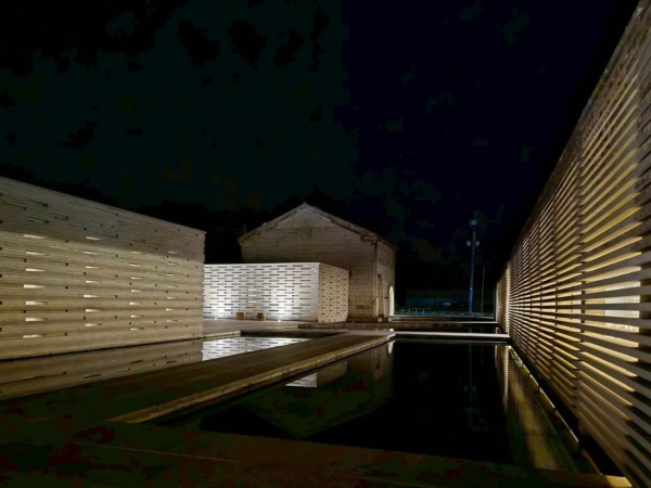 木製のルーバーと白い壁が特徴的な現代建築の夜景