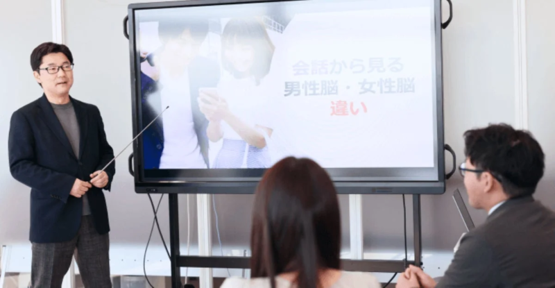 男性講師が「会話から見る男性脳・女性脳違い」についてプレゼンテーションを行う様子