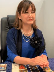 タロットカードが並べられたテーブルの前に座る女性