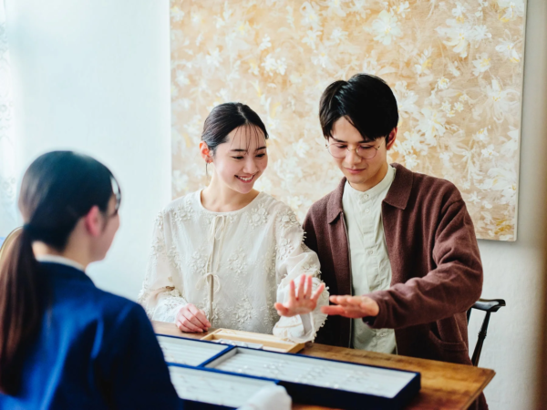 ジュエリーショップで指輪を選ぶカップルと店員